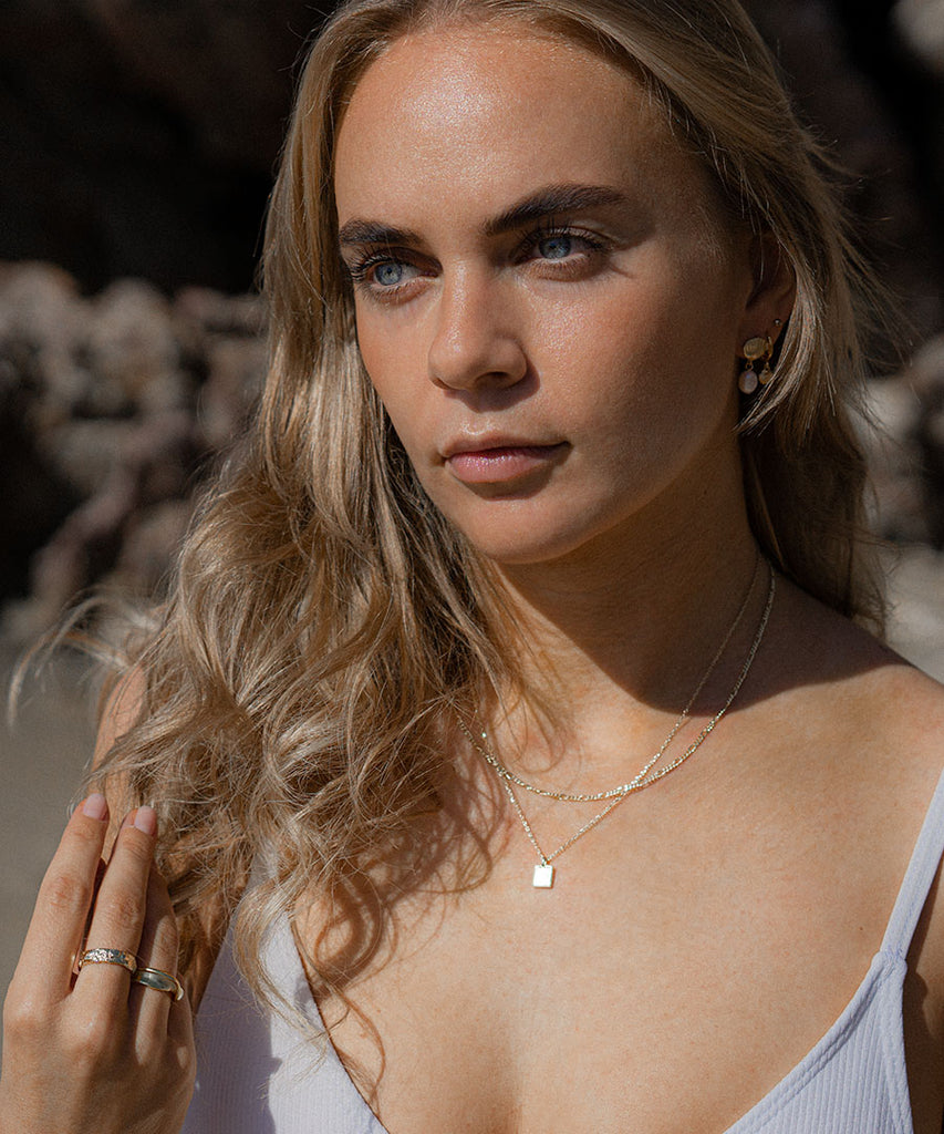 Model at the beach wearing gold plated minimal necklace